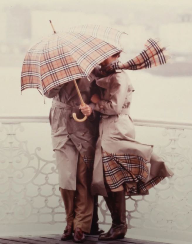 バーバリーチェックのアイテムを身につけたカップルがバーバリーチェックの傘をさしている画像