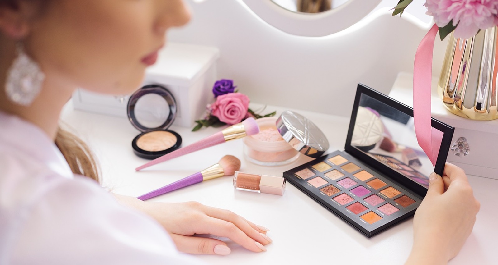 女性が鏡の前でいろいろなコスメを広げている画像