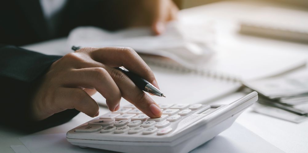 ペンを持ちながら電卓を叩いている画像